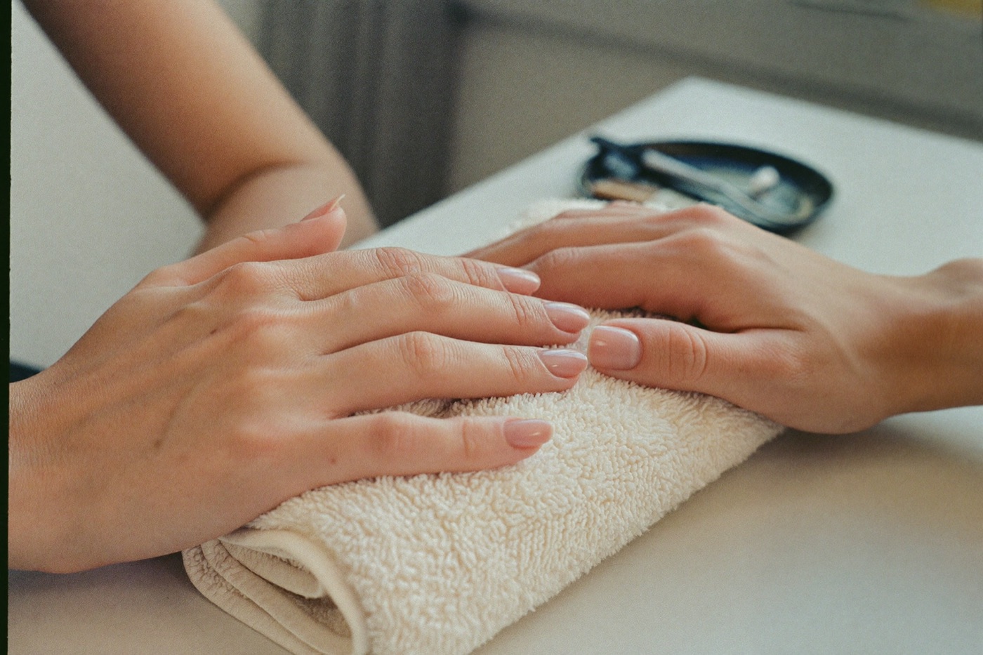 Close-up of hands resting after a natural manicure in warm daylight.