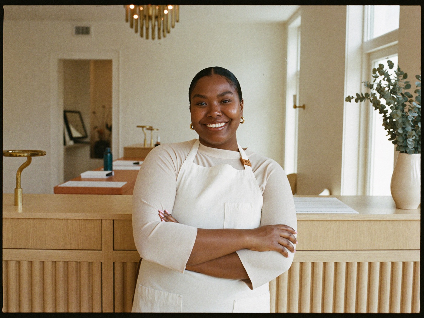 A beauty professional standing at the reception desk of a calm, modern salon.
